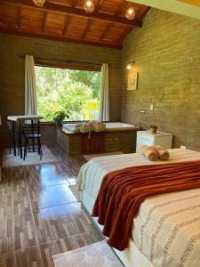 een slaapkamer met twee bedden, een tafel en een raam bij Refúgio com Hidro, Lareira, Café da Manhã e Vista da Natureza in Santo Antônio do Pinhal