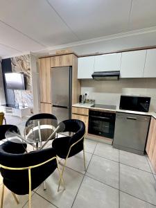 a kitchen with a glass table and black chairs at The Blyde 104 in Pretoria
