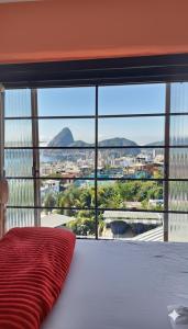 a bed with a red pillow in front of a large window at Hostel Tavares Bastos in Rio de Janeiro