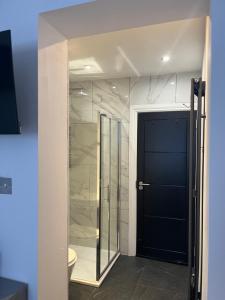 Un baño con ducha de cristal y puerta negra. en Double Guest Room 40 minutes from Central London, en Chessington