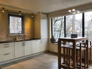 a kitchen with white cabinets and a table and windows at Modern holiday home 5 rooms in Durbuy +17 photos