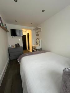 Un dormitorio con una cama blanca y una cocina. en Double Guest Room 40 minutes from Central London, en Chessington