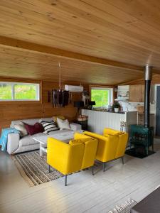 a living room with yellow chairs and a couch at Charming cabin by the sea in Lofoten in Sandsletta