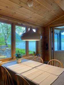 a dining room with a table with chairs and aendant light at Charming cabin by the sea in Lofoten in Sandsletta +39 photos
