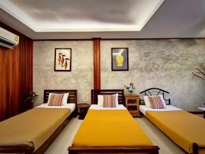2 Betten in einem Zimmer mit gelben Betten in der Unterkunft Phakphing Erawan Homestay - พักพิง เอราวัณ โฮมสเตย์ in Tha Kradan