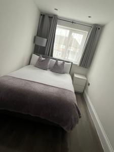 Una cama en una habitación pequeña con ventana. en Double Guest Room 40 minutes from Central London, en Chessington