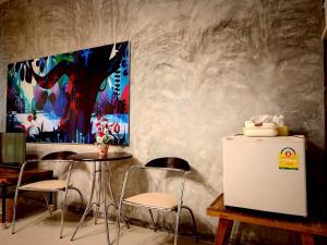a room with a table and chairs and a painting at Phakphing Erawan Homestay - พักพิง เอราวัณ โฮมสเตย์ in Tha Kradan