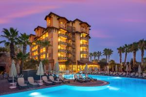 a hotel with a pool and chairs and palm trees at Villa Side Hotel in Side