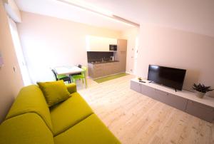 sala de estar con sofá amarillo y TV en Appartamenti Aosta, en Aosta