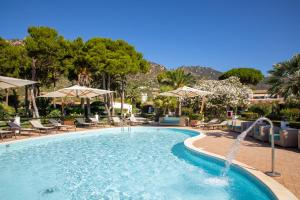 a pool with chairs and umbrellas in a resort at Cormoran Resort Villasimius in Villasimius