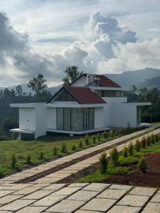 a white house with a red roof and a road at Ozone The Misty Villa - Hill View in Coonoor
