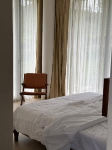 a bedroom with a bed and a chair next to a window at Ozone The Misty Villa - Hill View in Coonoor