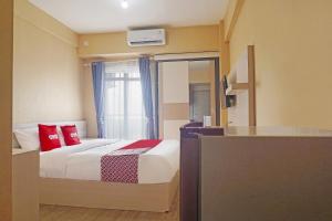 a bedroom with a bed with red pillows and a window at OYO 94925 Jp Apartment in Kedungbadak