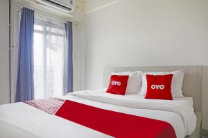 a bedroom with a large bed with two red pillows at OYO 94925 Jp Apartment in Kedungbadak