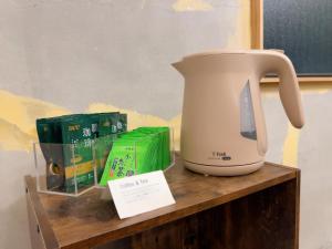 Eine Kaffeekanne steht auf einem Holzregal neben Büchern. in der Unterkunft ゲストハウス ブランク Guest House BLANC in Hiroshima