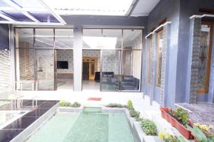 a house with a swimming pool in the courtyard at Hotel O 94911 Syariah Anggrek Guest House in Lebakwangi