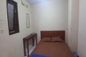 a small bedroom with a bed and a table at Hotel O 94911 Syariah Anggrek Guest House in Lebakwangi