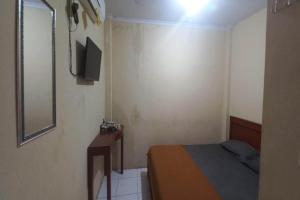 a small bedroom with a bed and a mirror at Hotel O 94911 Syariah Anggrek Guest House in Lebakwangi