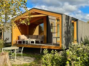 a tiny house with a patio and a table at 101 Tiny House Elbhütte mit Wiesenblick in Bleckede