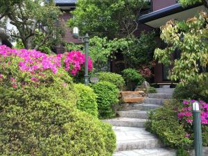 a garden with pink flowers in front of a house at Hananobou Kinkakuji-michi in Kyoto