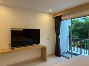 a bedroom with a flat screen tv and a balcony at Luna Resident in Ban Bang Phai +2 photos