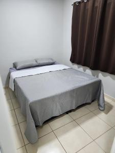 um quarto com uma cama com um cobertor cinzento em Comfortable house in a gated community em Rondonópolis