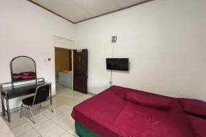 um quarto com uma cama, uma escrivaninha e uma televisão em OYO 94937 Garuda Homestay Syariah em Demangan