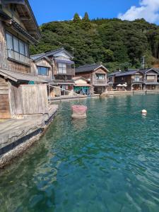 un cuerpo de agua con casas y un barco en él en Morifuneya Ine - 森舟屋 伊根 -, en Kameshima