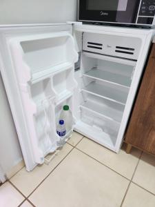 um frigorífico aberto com uma garrafa de água em Comfortable house in a gated community em Rondonópolis