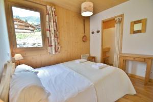 a bedroom with a bed in a room with a window at Refuge Les Echelles E4 in Le Grand-Bornand