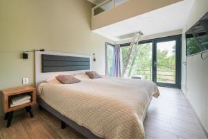 a bedroom with a large bed and a large window at Exclusive Duin Villa - 6p - Direct bij Natuur & Strand - Villa 70 in Ouddorp
