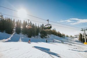 a group of people riding a ski lift in the snow at Hotel Krvavec in Cerklje na Gorenjskem