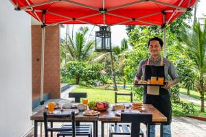 a man holding a tray of food on a table at Mahogany by Exuberance Stays in Wayanad
