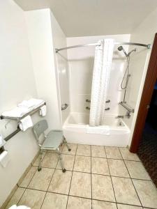 a small bathroom with a shower and a chair at SureStay by Best Western Prince Frederick in Prince Frederick +4 photos
