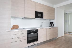 une cuisine avec des armoires en bois et un four à plaques de cuisson dans l'établissement 12th Floor Sauna Retreat with Stunning City Views, à Tampere