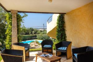 a patio with chairs and a table and a pool at Sardegna è - Beach Rooms LE in Olbia