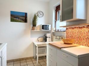 Una cocina con gabinetes blancos y un microondas. en Haus Muschelnest, en Sahlenburg