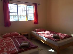 two beds in a room with a window at steps Self-Catering Accommodation in Okakarara