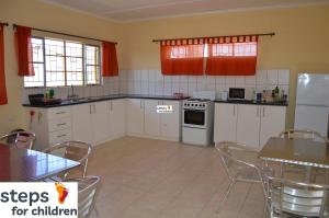 a kitchen with white appliances and a table and chairs at steps Self-Catering Accommodation in Okakarara