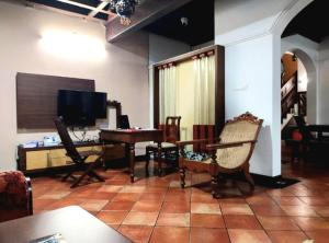 een woonkamer met een tafel, stoelen en een televisie bij The Boho Cochin in Cochin