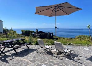 - une table de pique-nique, 2 chaises et un parasol dans l'établissement Casa Cachalote - Ferienhaus auf den Azoren, à São Caetano