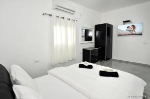 a white bedroom with a bed and a tv at אגם בגליל - וילה ו-3 סוויטות עם בריכה מחוממת בעבדון in Wadi Keren