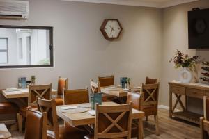 a restaurant with tables and chairs and a clock on the wall at Santai guesthouse in Brits