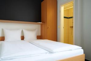 a bedroom with a bed with white sheets and a bathroom at Bettenburg Hotel Hamburg in Hamburg