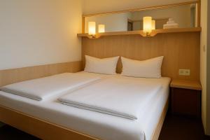 a bedroom with a bed with white sheets and a mirror at Bettenburg Hotel Hamburg in Hamburg