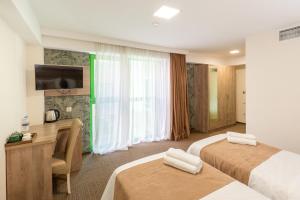 Una habitación de hotel con dos camas, un escritorio y un televisor. en Hotel Somi Inn, en Tiflis