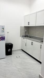 une cuisine avec des armoires blanches et un réfrigérateur dans l'établissement شقة راقية بغرفة نوم وصالة مريحة, à Hafr Al Baten