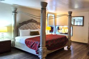 a bedroom with a canopy bed with a red blanket at Capital O Elite Inn & Suites South Holland I 94 in South Holland