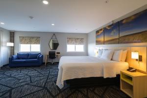 a hotel room with a bed and a blue couch at Days Inn by Wyndham Jackson in Jackson +20 photos