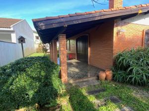 a brick house with a blue awning at Seu Lar em Imbè in Imbé